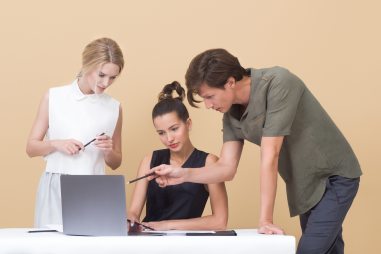 Image of two adults helping one student on laptop